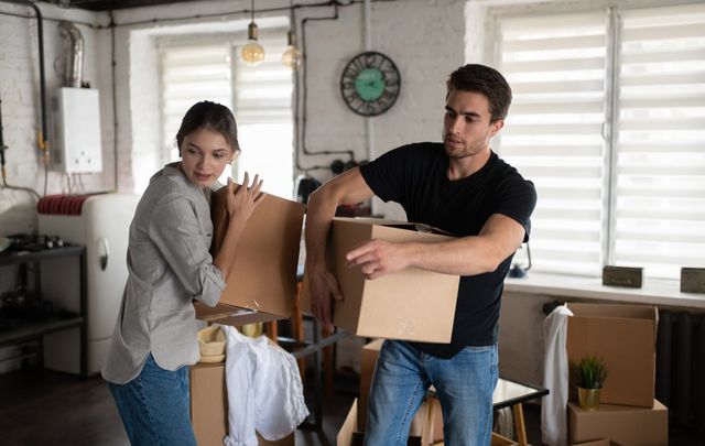 young-couple-carrying-carton-boxes-during-relocati-QFS6VTN-640w
